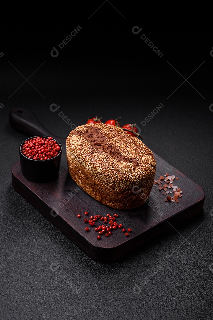 Delicioso pão integral crocante fresco com sementes e grãos sobre um fundo escuro de concreto