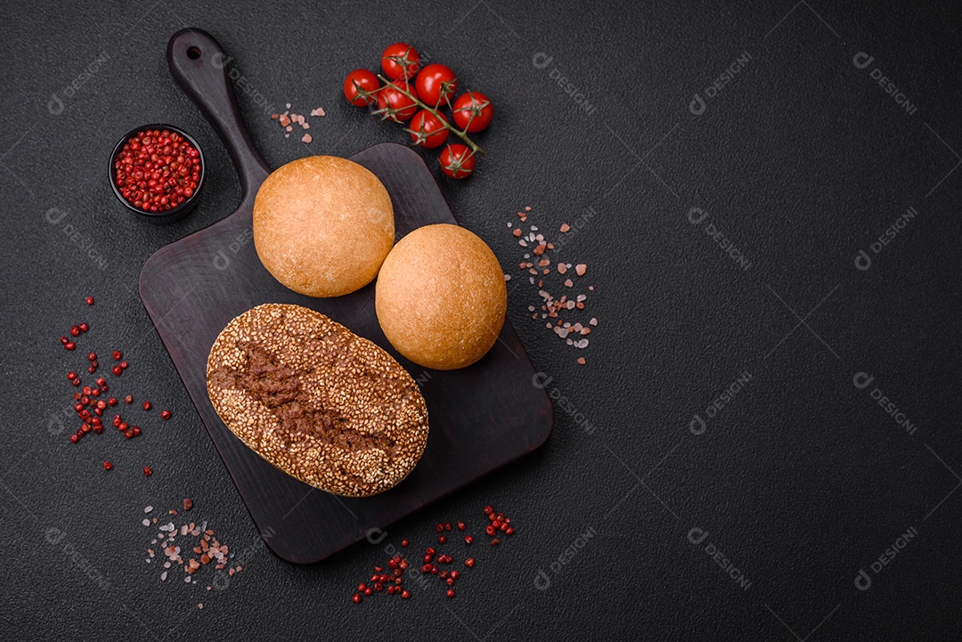 Delicioso pão redondo branco crocante fresco com sementes e grãos sobre um fundo escuro de concreto