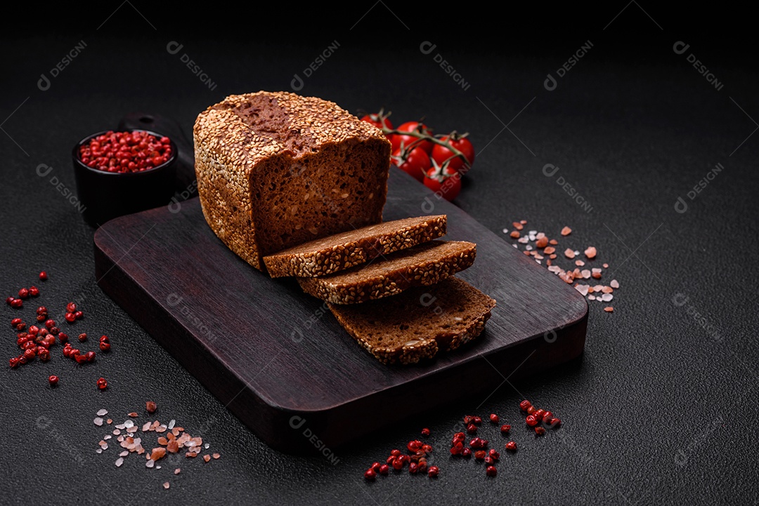 Delicioso pão integral crocante fresco com sementes e grãos sobre um fundo escuro de concreto