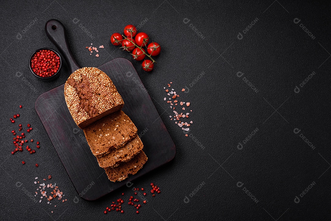 Delicioso pão integral crocante fresco com sementes e grãos sobre um fundo escuro de concreto