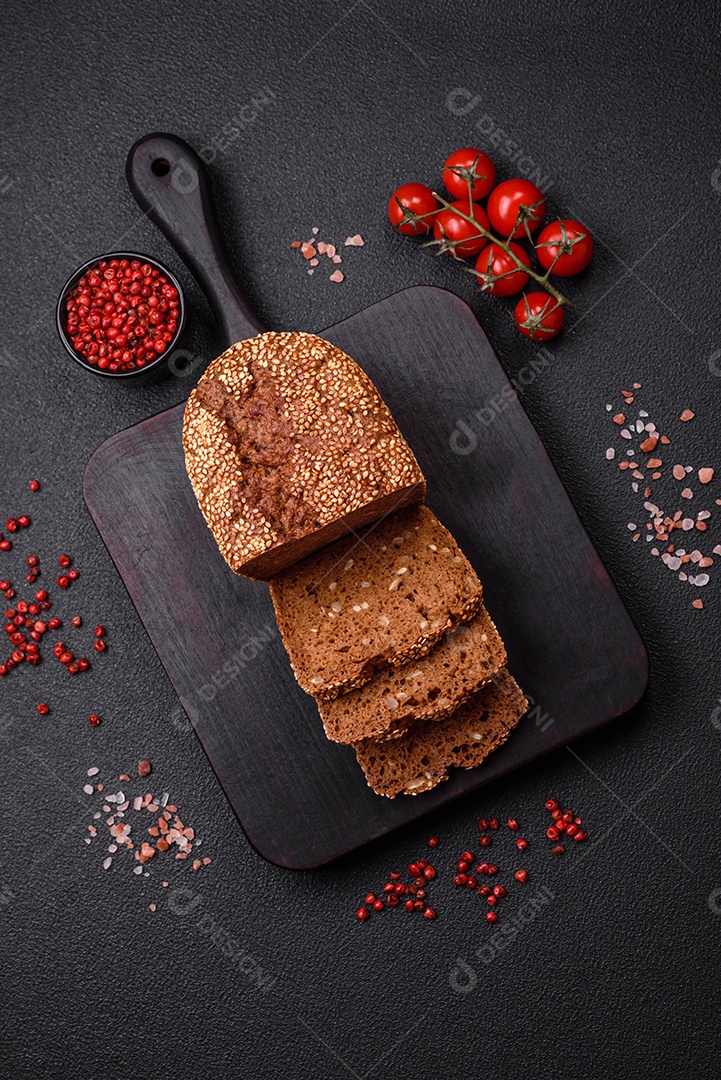 Delicioso pão integral crocante fresco com sementes e grãos sobre um fundo escuro de concreto