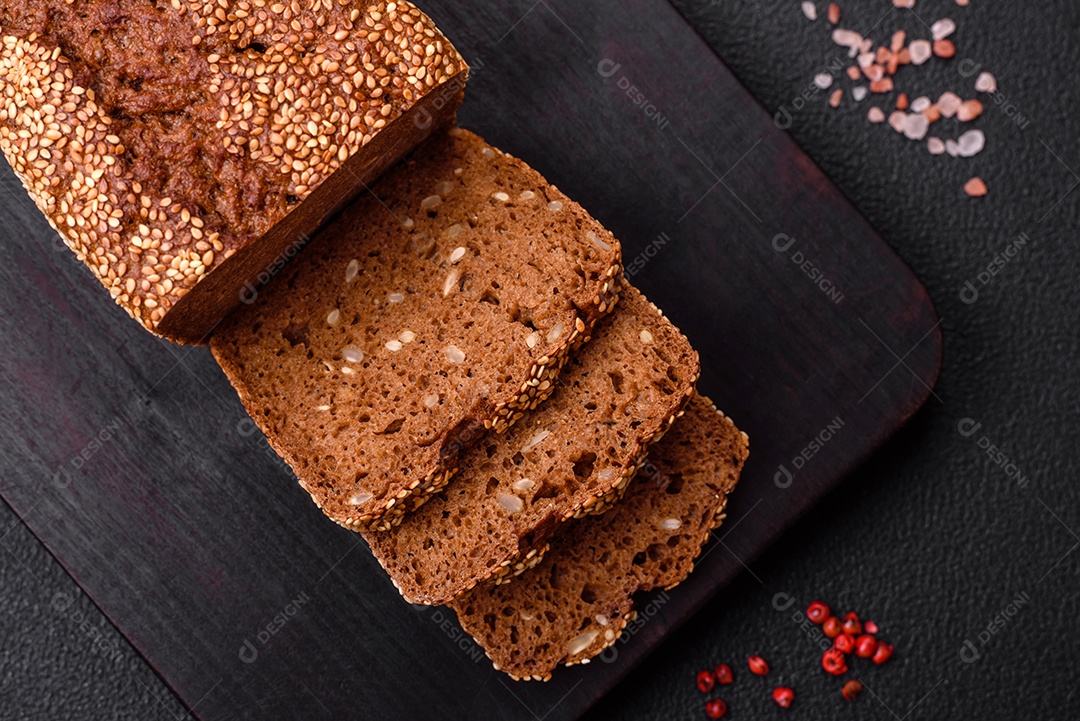 Delicioso pão integral crocante fresco com sementes e grãos sobre um fundo escuro de concreto