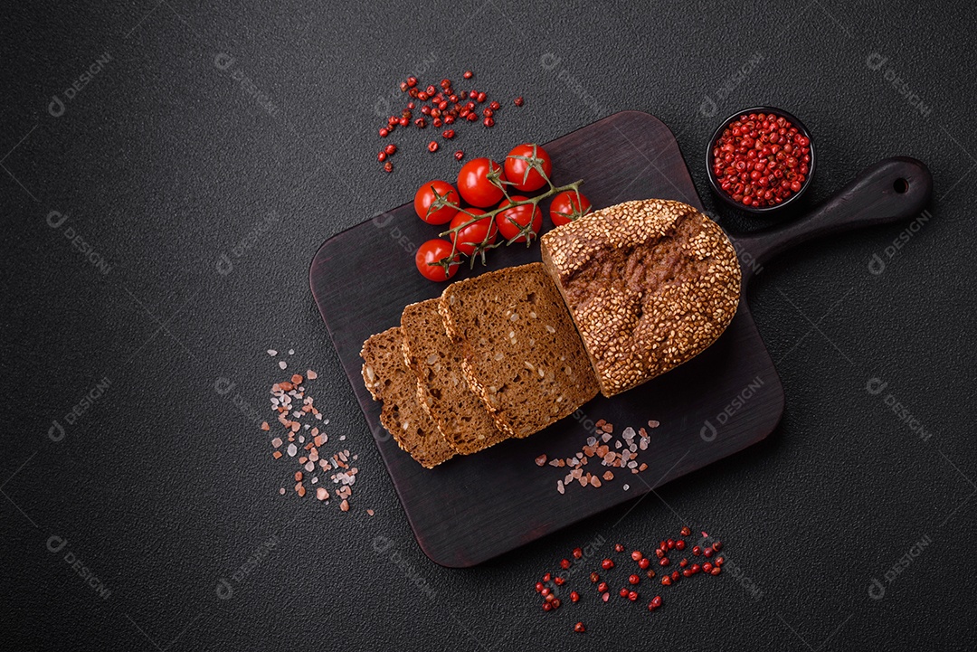 Delicioso pão integral crocante fresco com sementes e grãos sobre um fundo escuro de concreto