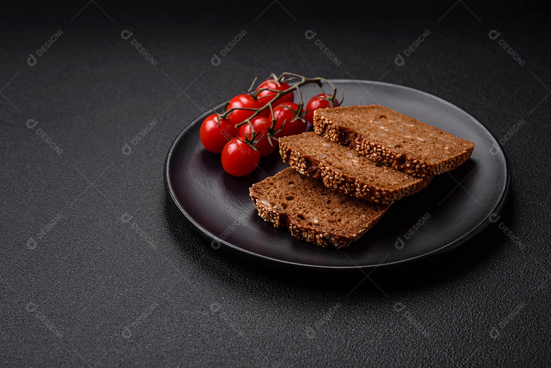 Delicioso pão integral crocante fresco com sementes e grãos sobre um fundo escuro de concreto