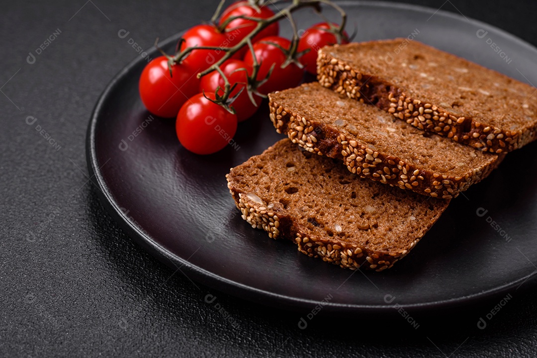 Delicioso pão integral crocante fresco com sementes e grãos sobre um fundo escuro de concreto