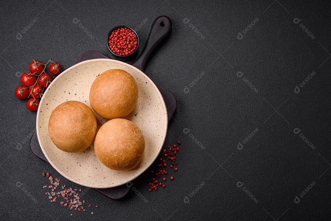 Delicioso pão redondo branco crocante fresco com sementes e grãos sobre um fundo escuro de concret