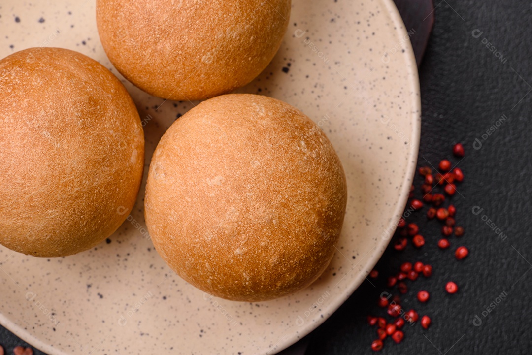 Delicioso pão redondo branco crocante fresco com sementes e grãos sobre um fundo escuro de concreto