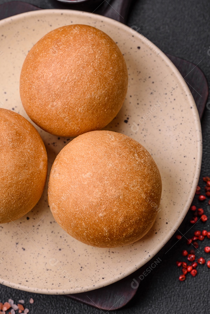 Delicioso pão redondo branco crocante fresco com sementes e grãos sobre um fundo escuro de concreto