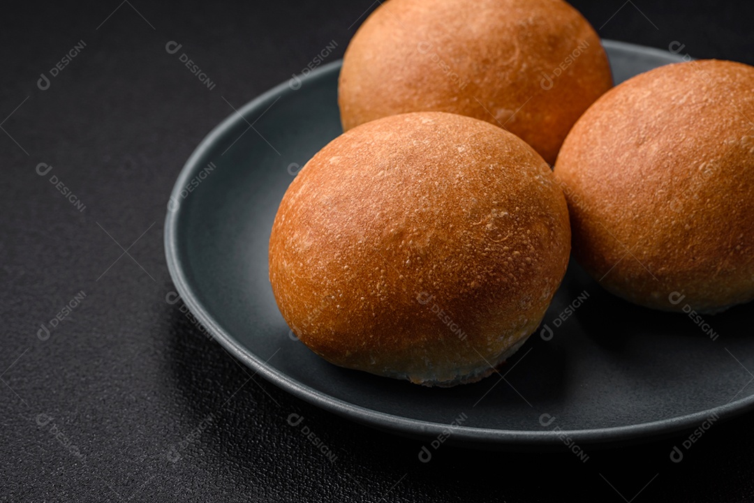 Delicioso pão redondo branco crocante fresco com sementes e grãos sobre um fundo escuro de concret