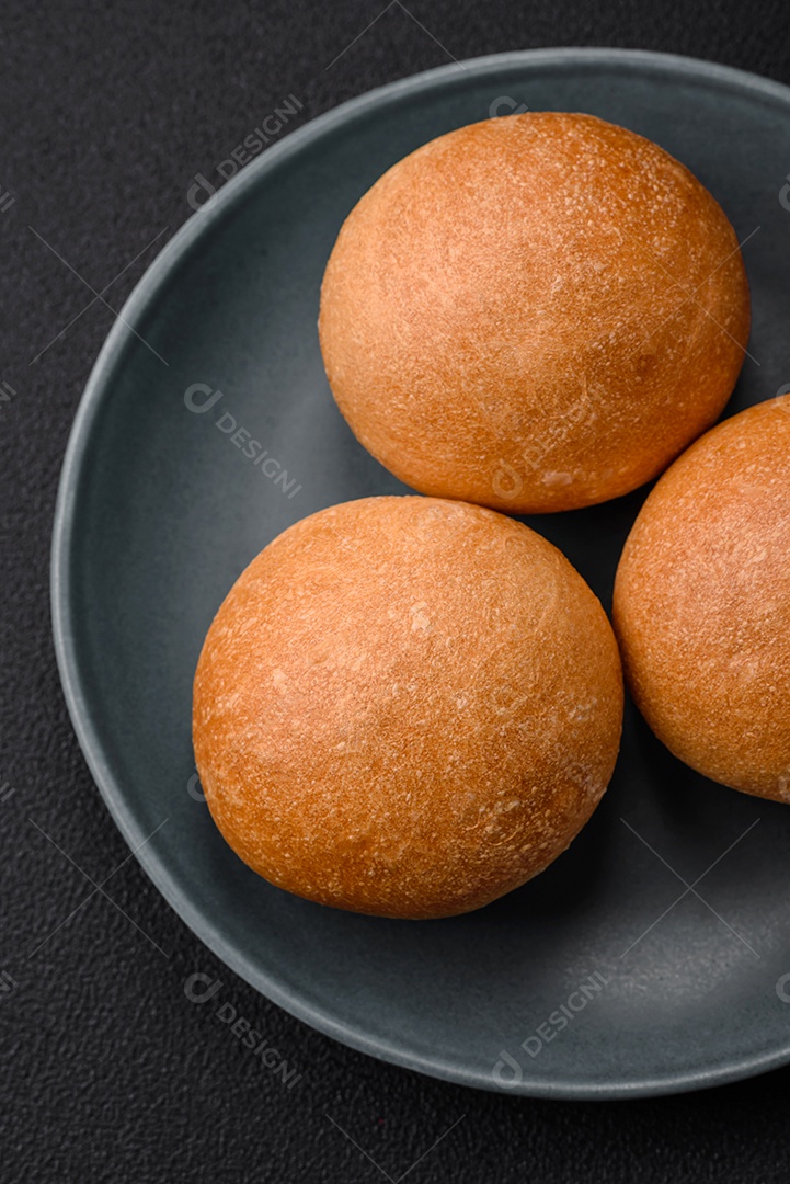 Delicioso pão redondo branco crocante fresco com sementes e grãos sobre um fundo escuro de concreto