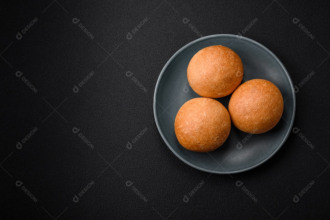 Delicioso pão redondo branco crocante fresco com sementes e grãos sobre um fundo escuro de concreto