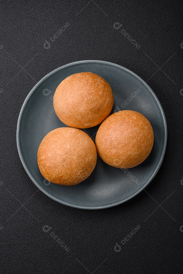 Delicioso pão redondo branco crocante fresco com sementes e grãos sobre um fundo escuro de concreto
