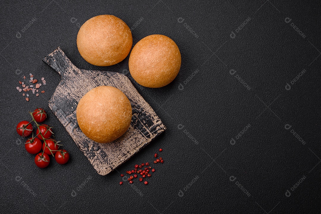Delicioso pão redondo branco crocante fresco com sementes e grãos sobre um fundo escuro de concreto