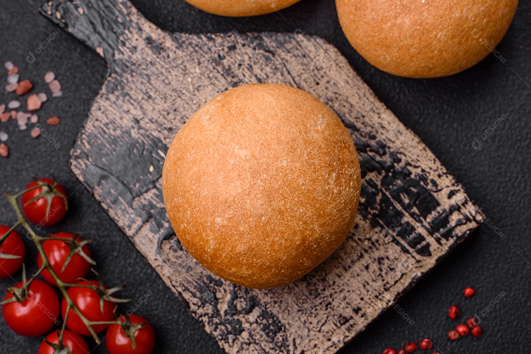 Delicioso pão redondo branco crocante fresco com sementes e grãos sobre um fundo escuro de concreto