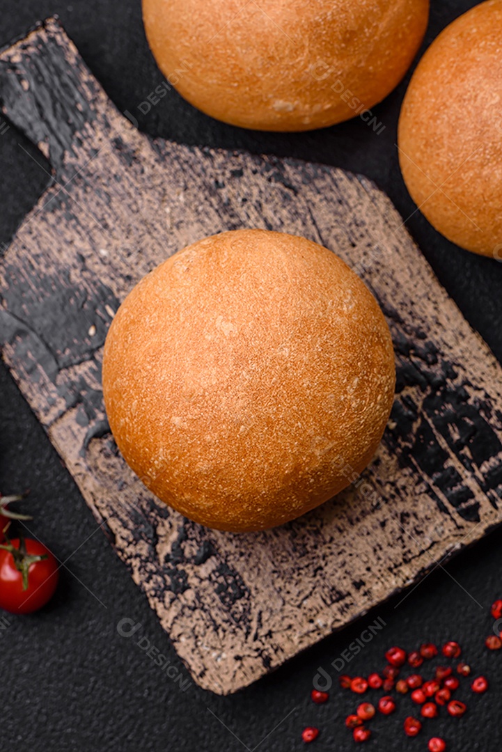 Delicioso pão redondo branco crocante fresco com sementes e grãos sobre um fundo escuro de concreto