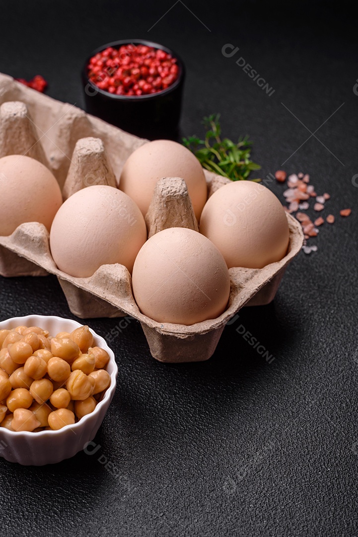 Ovos de galinha crus em uma caixa, tomate cereja, grão de bico, especiarias, sal e ervas. Ingredientes para um café da manhã delicioso e nutritivo