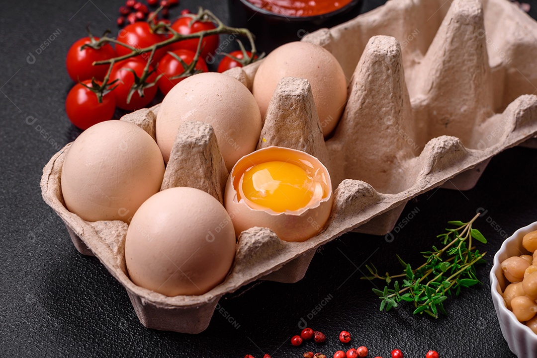 Ovos de galinha crus em uma caixa, tomate cereja, grão de bico, especiarias, sal e ervas.