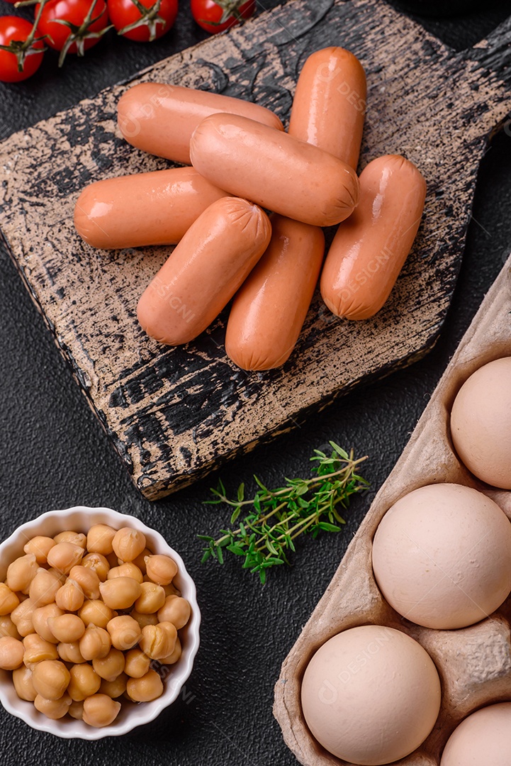 Ovos de galinha crus em uma caixa, tomate cereja, grão de bico, especiarias, sal e ervas.