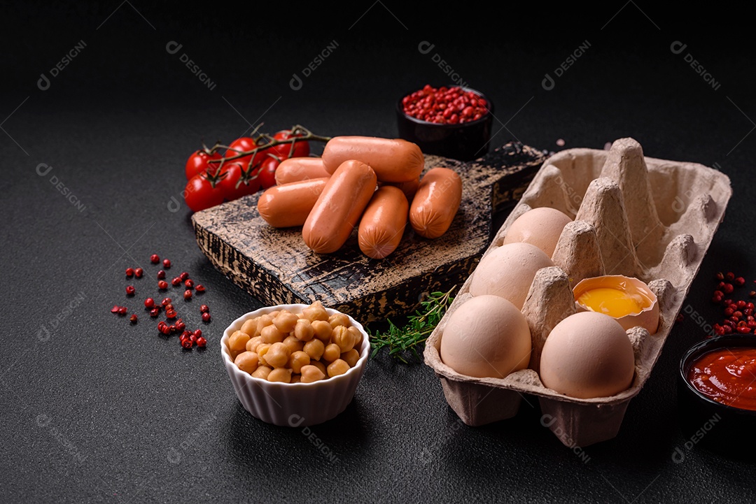 Ovos de galinha crus em uma caixa, tomate cereja, grão de bico, especiarias, sal e ervas.