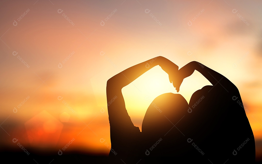 Silhueta de casal fez as mãos em forma de coração em fundo laranja pastel e Dia dos Namorados