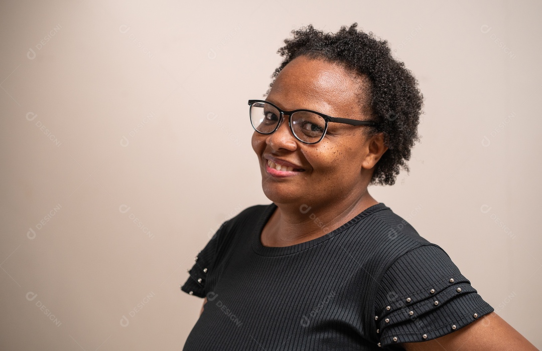 Mulher negra de óculos sorrindo em fundo pastel.