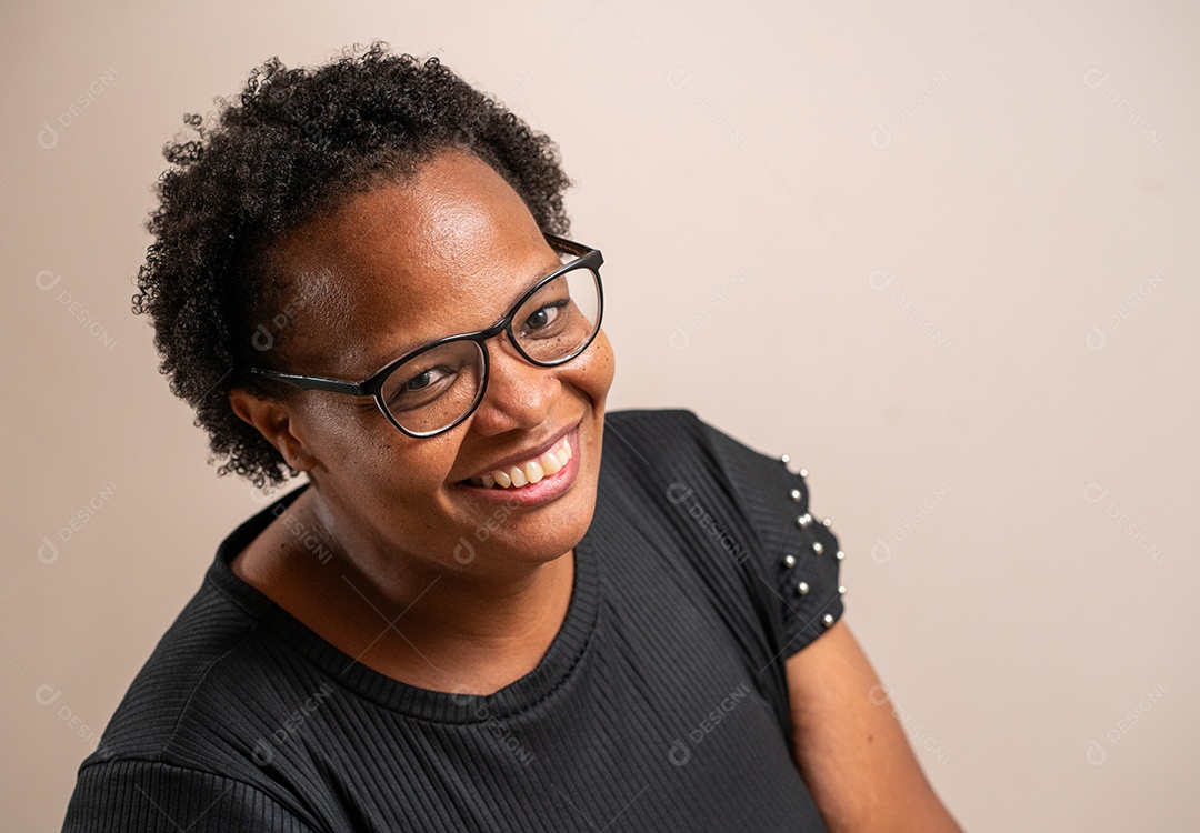 Mulher negra de óculos sorrindo em fundo pastel.