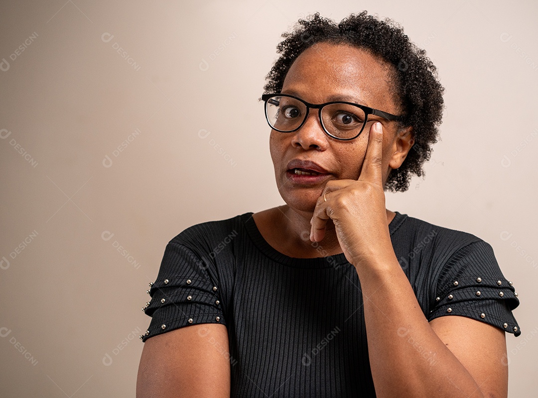 Mulher negra pensando com a mão no rosto em fundo pastel.
