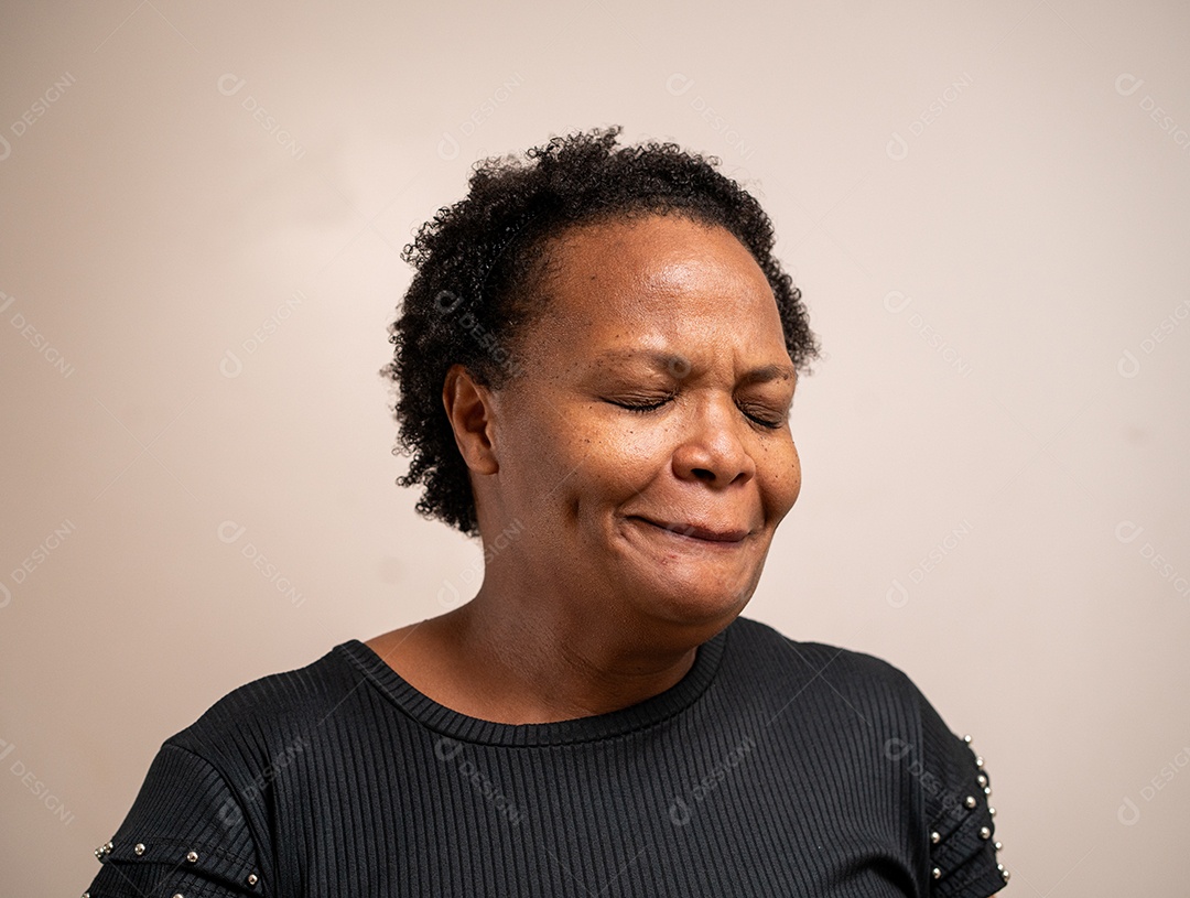 Mulher negra com olhos fechados com expressão triste em fundo pastel.