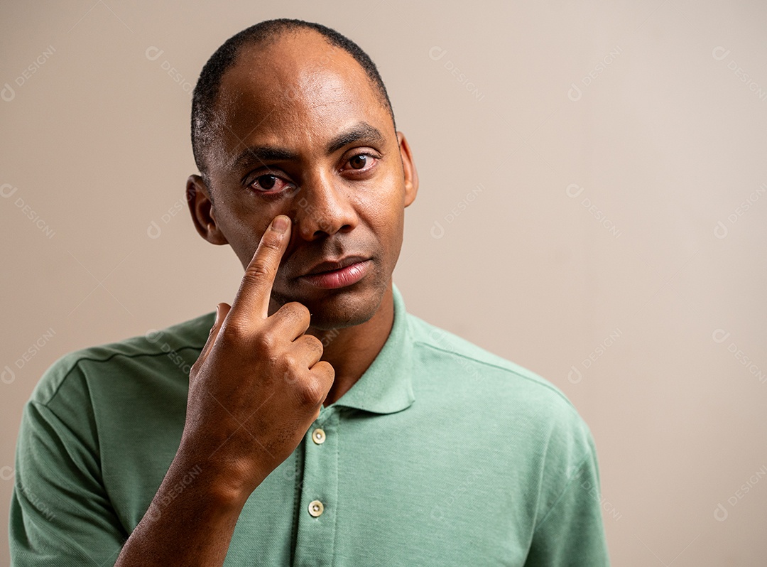 Homem apontando para o olho em um fundo pastel.