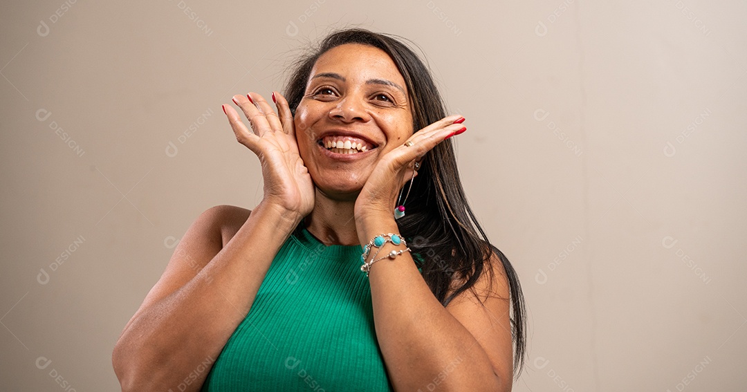 Mulher sorrindo com as mãos no rosto em fundo pastel.