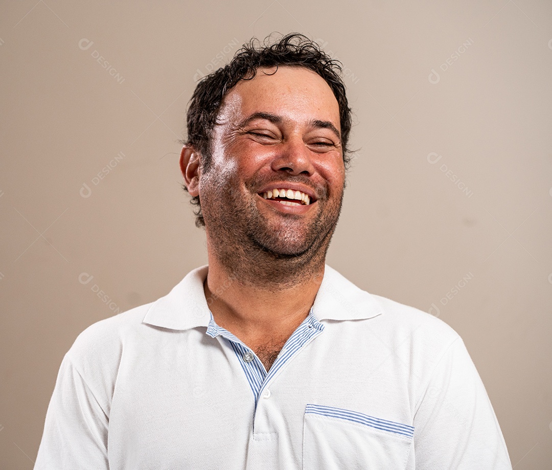 Homem com barba por fazer sorrindo com os olhos fechados em fundo pastel.