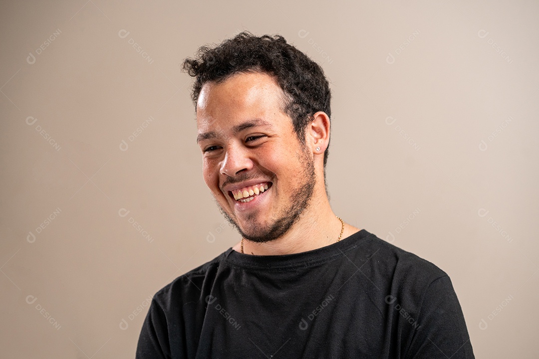 Jovem com barba por fazer sorrindo em fundo pastel.