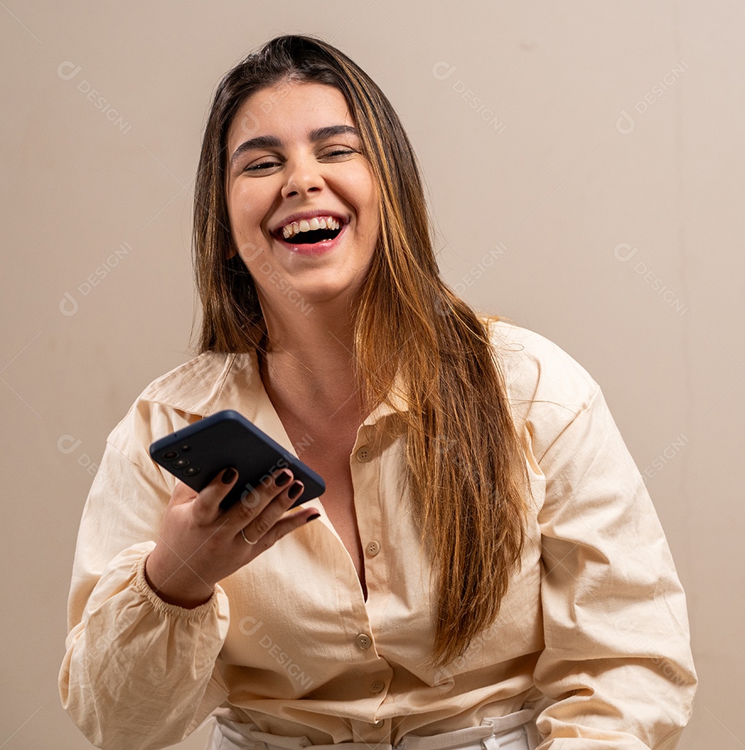 Rindo jovem segurando smartphone em fundo pastel.