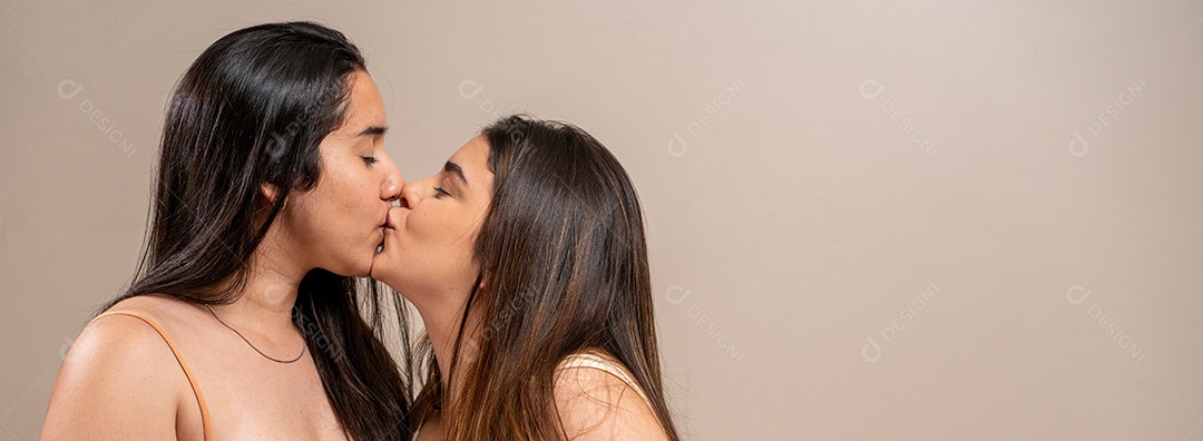 Mulheres jovens dando um beijinho em fundo pastel.