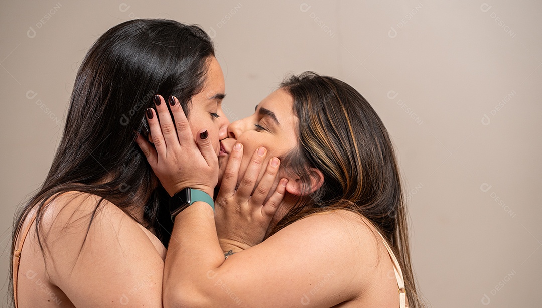 Mulheres jovens dando um beijinho em fundo pastel.