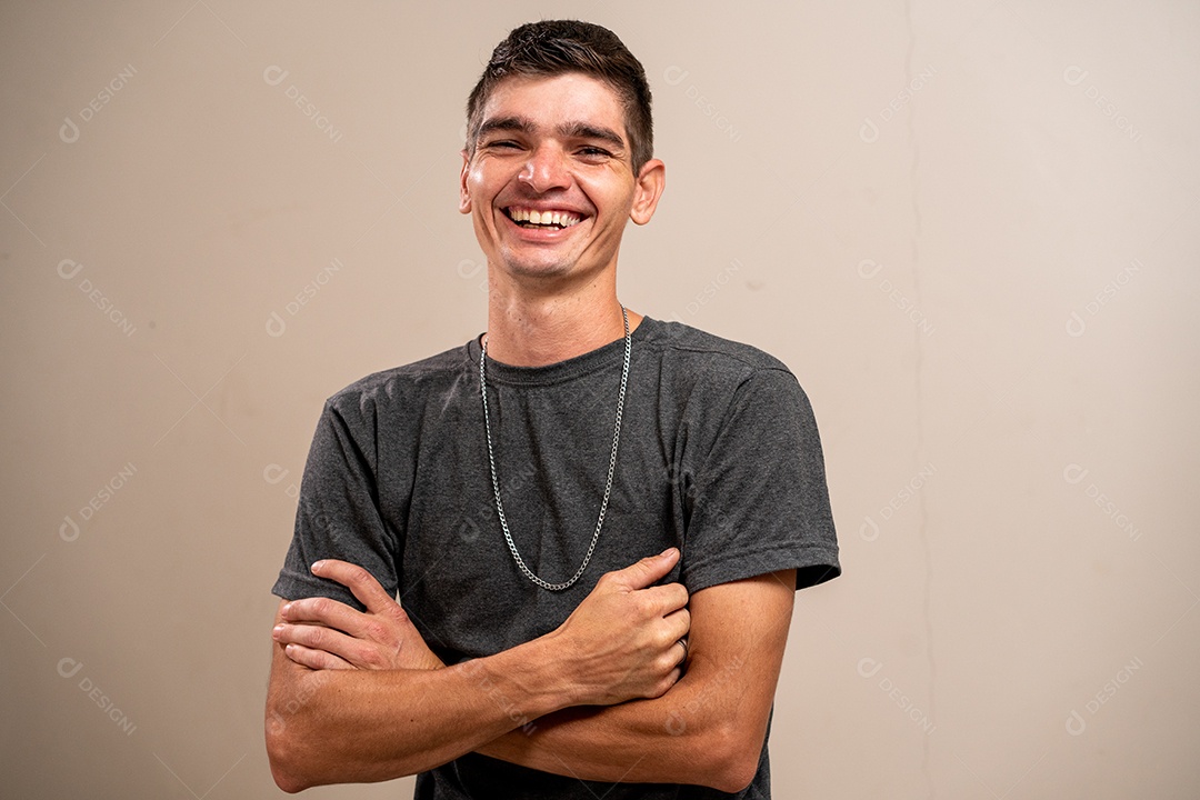 Jovem sorrindo com os braços cruzados em fundo pastel.