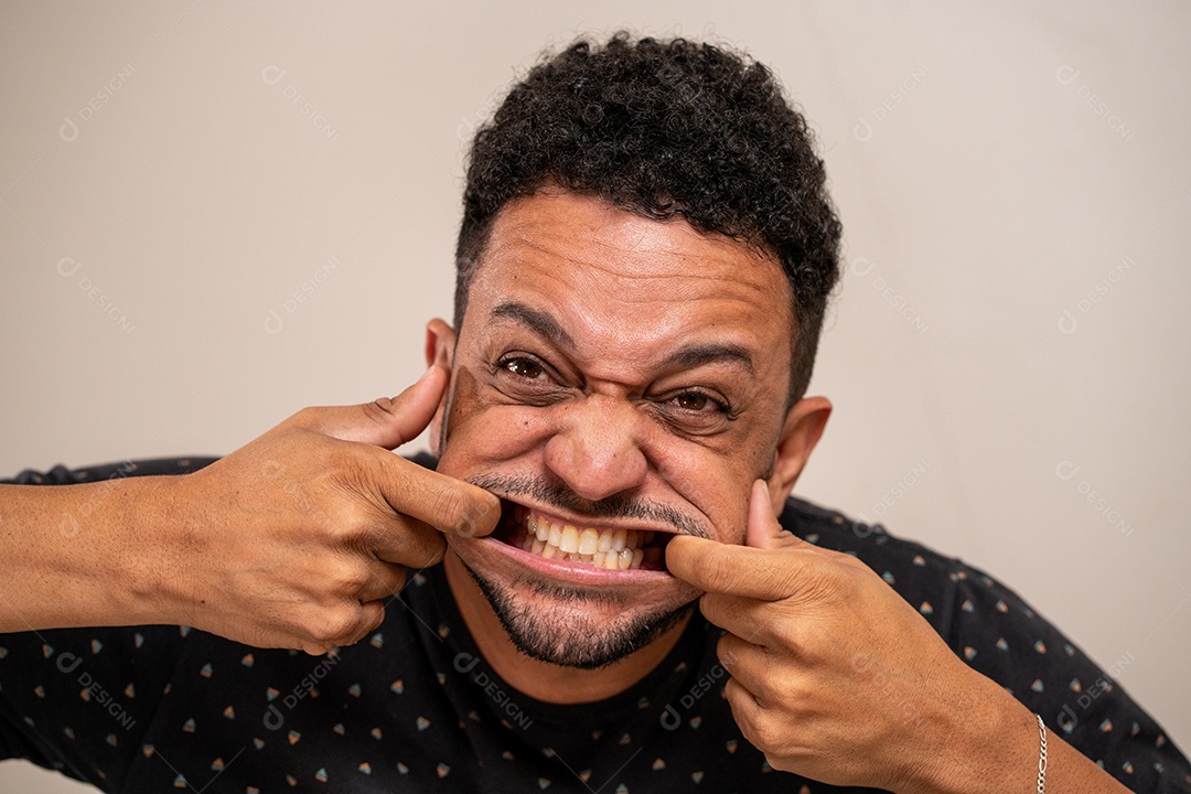 Homem moreno fazendo careta em fundo pastel.