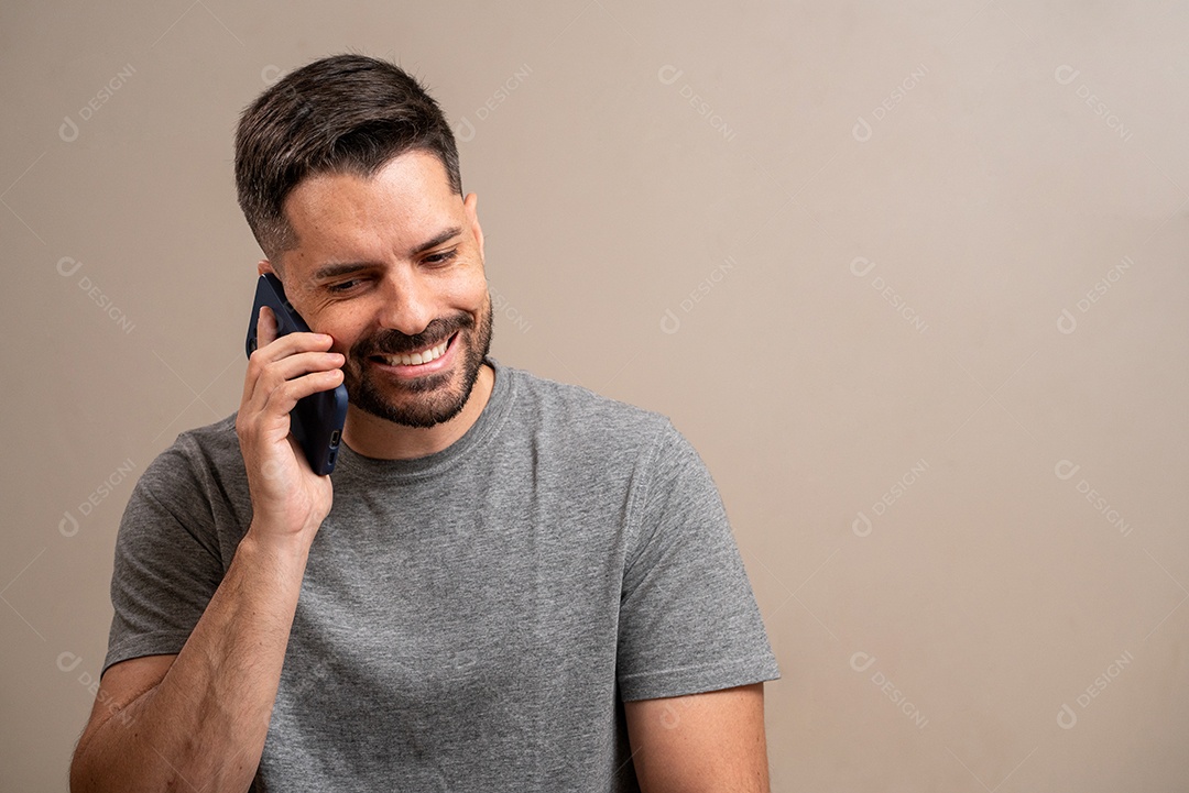 Homem sorridente falando no celular em fundo pastel.