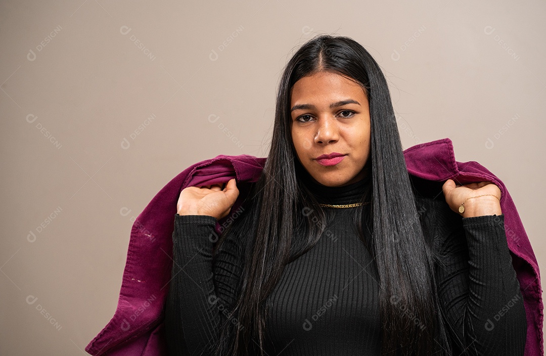 Jovem morena segurando uma jaqueta em fundo pastel