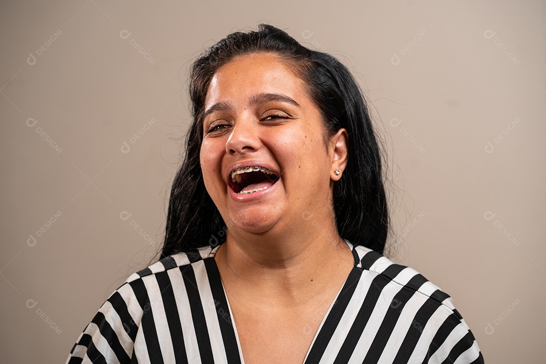 Jovem morena com aparelho sorrindo em fundo pastel.