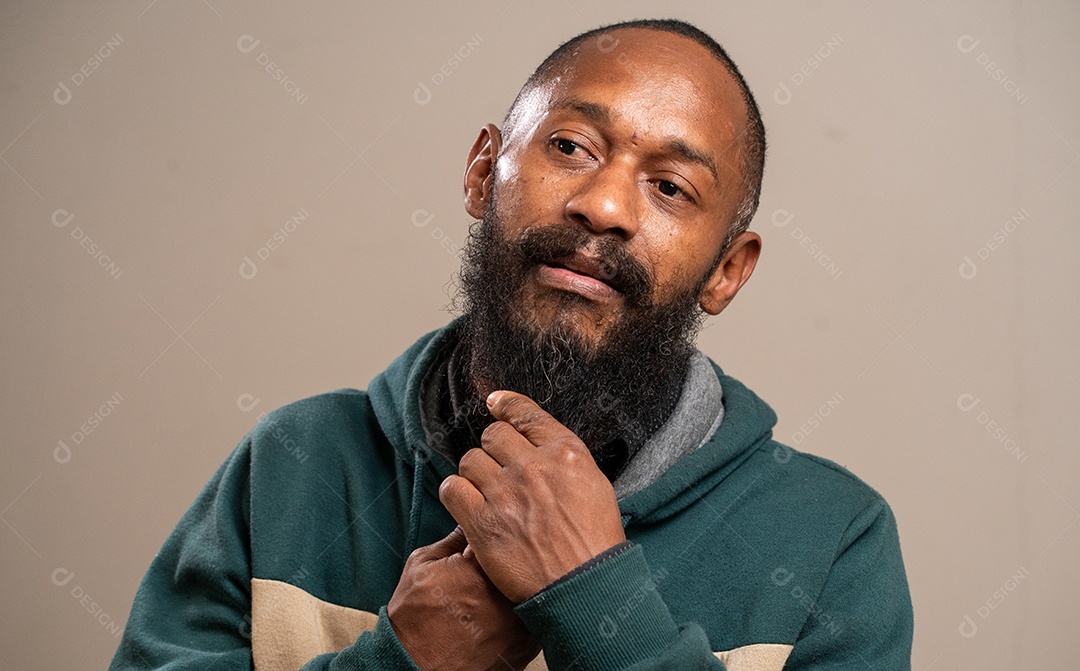 Homem negro barbudo sorrindo em fundo pastel.