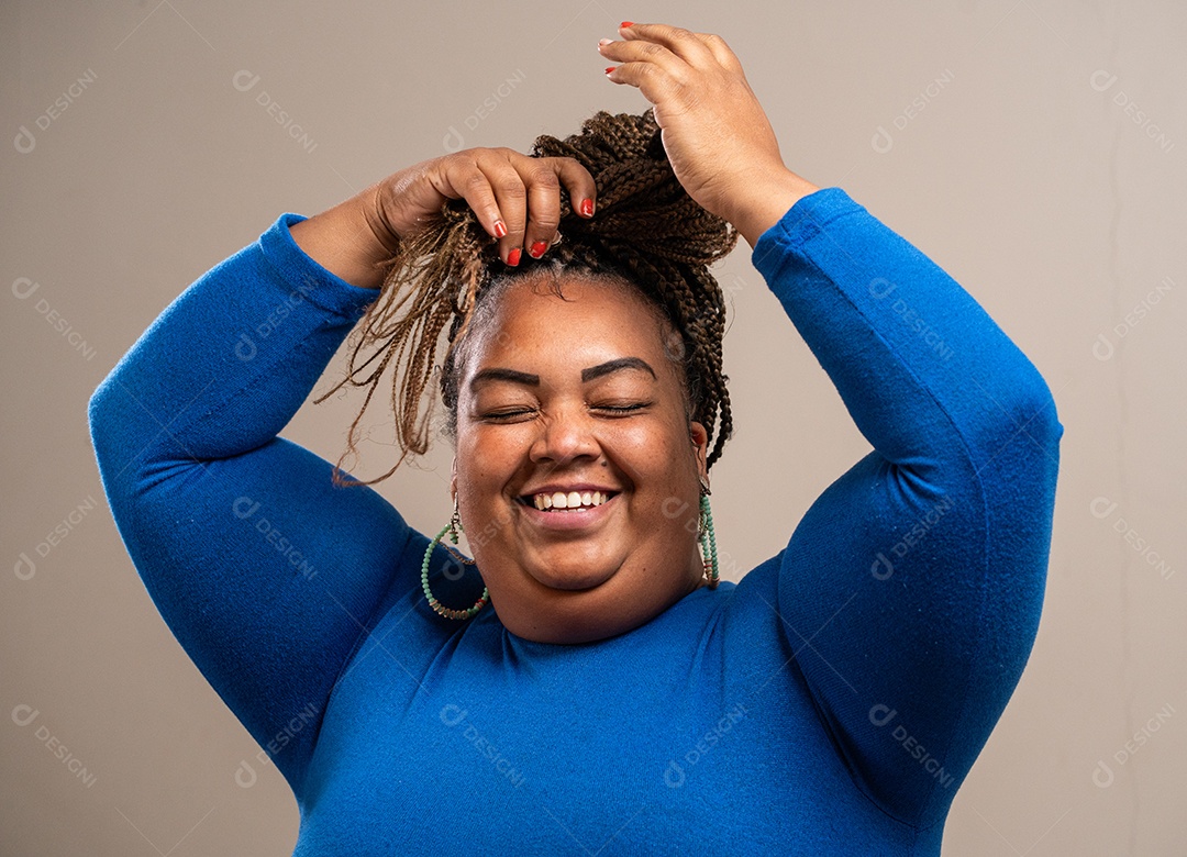 Jovem com tranças afro amarrando o cabelo em fundo pastel.