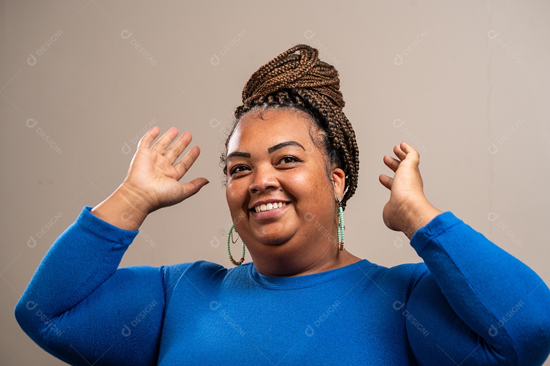 Jovem com tranças afro amarrando o cabelo em fundo pastel.
