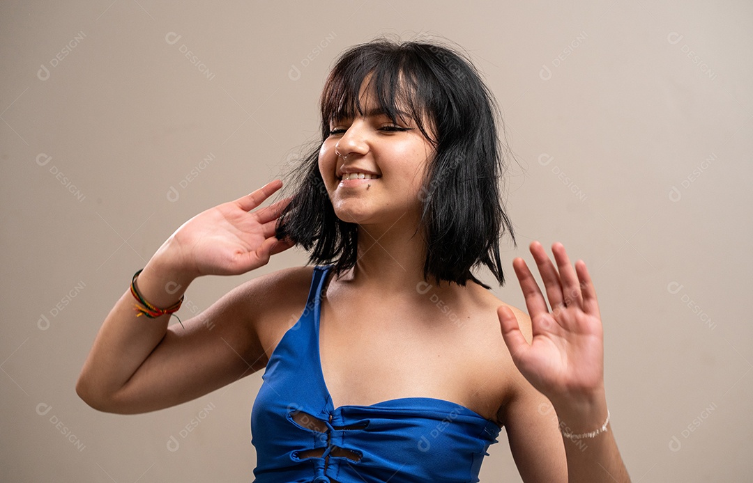 Menina com as mãos para cima e cabelos soltos em fundo pastel.