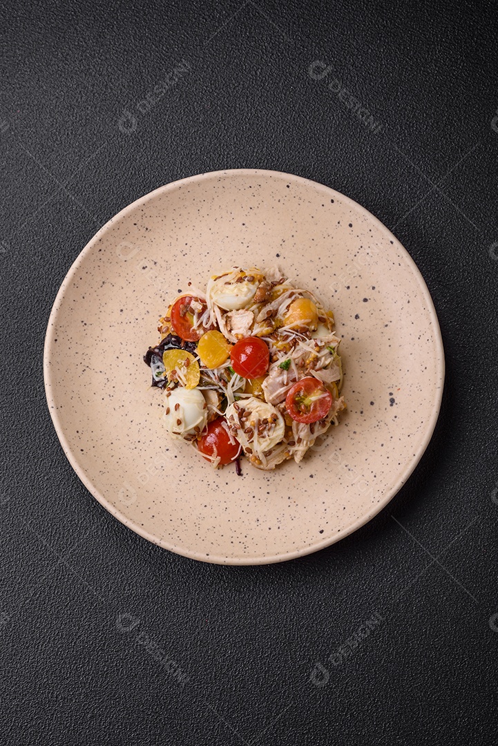 Deliciosa salada fresca com frango, ovos de codorna, tomate cereja, alface, sal e especiarias sobre fundo escuro de concreto