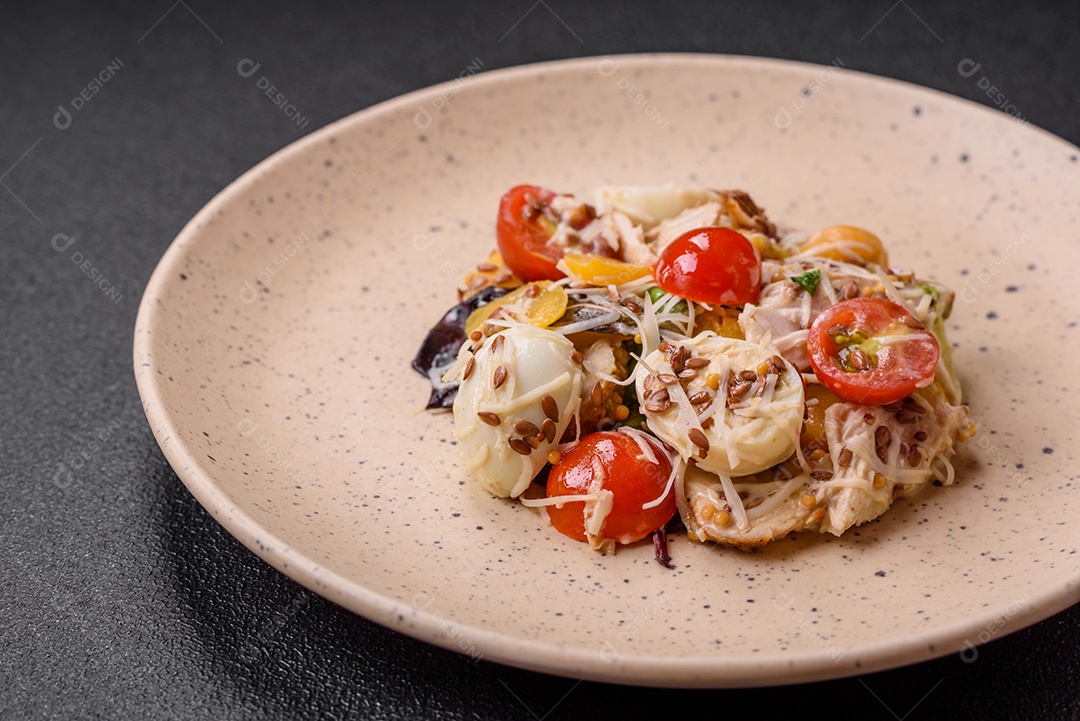 Deliciosa salada fresca com frango, ovos de codorna, tomate cereja, alface, sal e especiarias sobre fundo escuro de concreto