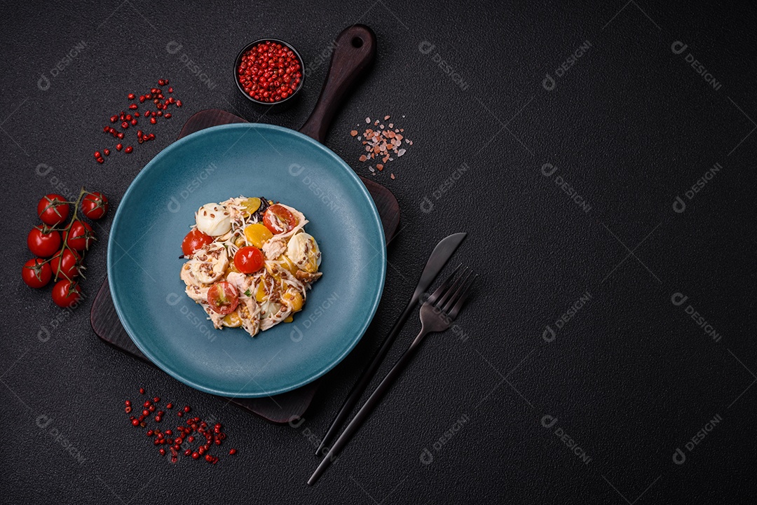 Deliciosa salada fresca com frango, ovos de codorna, tomate cereja, alface, sal e especiarias sobre fundo escuro de concreto