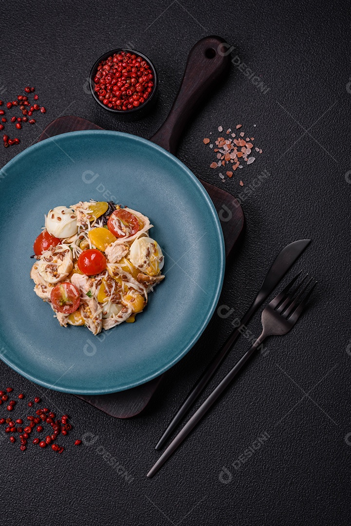 Deliciosa salada fresca com frango, ovos de codorna, tomate cereja, alface, sal e especiarias sobre fundo escuro de concreto