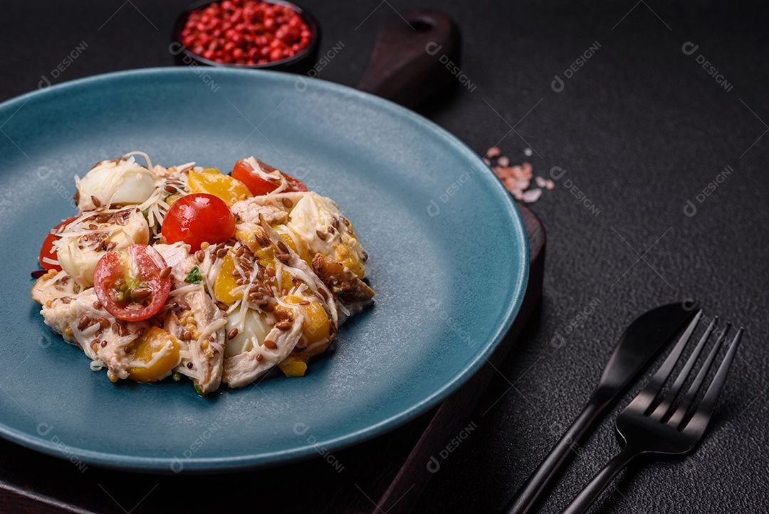 Deliciosa salada fresca com frango, ovos de codorna, tomate cereja, alface, sal e especiarias sobre fundo escuro de concreto