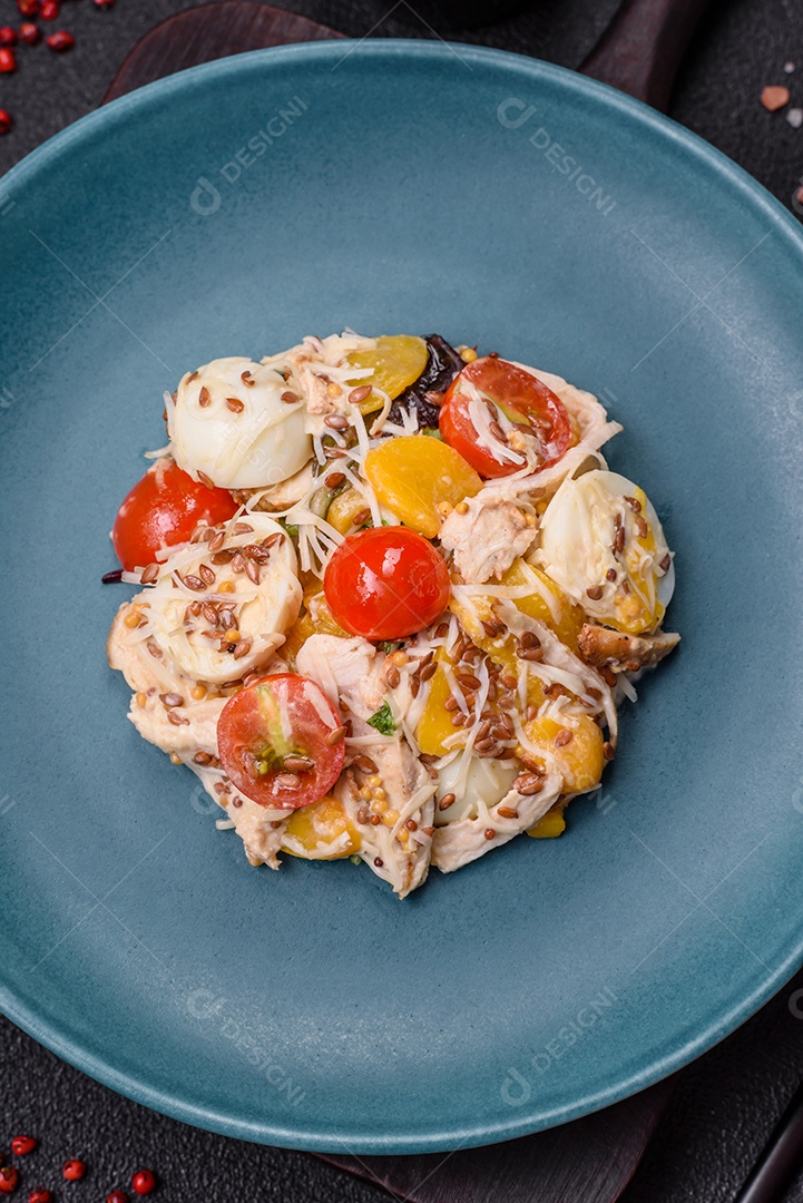 Deliciosa salada fresca com frango, ovos de codorna, tomate cereja, alface, sal e especiarias sobre fundo escuro de concreto